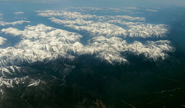 地表の飛行機からの眺め 雪に覆われた山々 — ストック写真