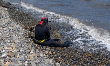 Dalgıç kıyıda oturur ve dalmaya hazırlanır..