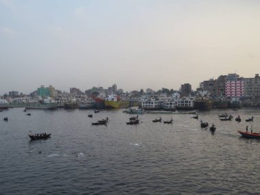 güçlü Buriganga nehir Sadarghat, gemiler, kıyıdan kıyıya geçerken küçük feribot tekne üzerinde alacakaranlıkta