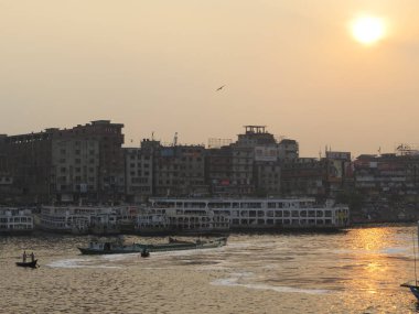 güçlü Buriganga nehir Sadarghat, gemiler, kıyıdan kıyıya geçerken küçük feribot tekne üzerinde alacakaranlıkta