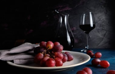 Kırmızı şarap, üzüm ve karanlık ortamda dekantör.