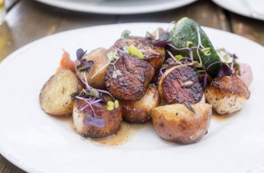 Kararmış pişmiş patates ile hizmet tarak kabak ve roka lahanası ile süslenmiş