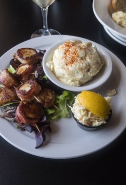 Izgara domuz pastırması lahana salatası ve kremalı patates salatası ile servis tarak sarılmış