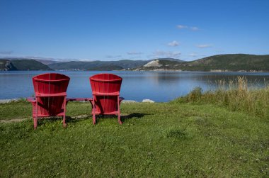 Two Red Adirondack Chairs With A View of Bonne Bay and Tablelands clipart