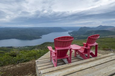 Two Red Adirondack Chairs on Top of the Lookout Trail in Gros Morne National Park Newfoundland clipart