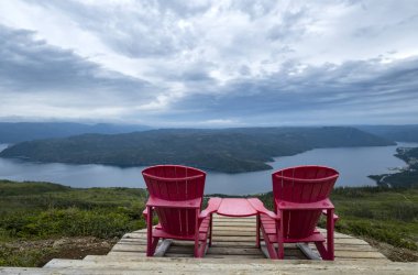 Two Red Adirondack Chairs on Top of the Lookout Trail in Gros Morne National Park Newfoundland clipart