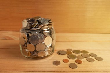 Bir cam şişe ahşap zemin üzerinde tasarruf paralar içinde