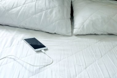 Beyaz yatakta akıllı telefon şarj