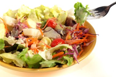 Taze salata ve sosu çatal üzerinde siyah susam ve salata tabağı ve beyaz arka plan üzerinde
