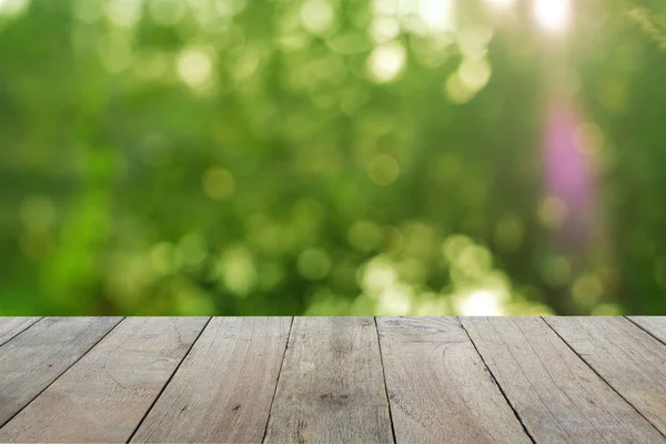 Old wooden table foreground with blurred green bokeh background, empty space Place a product. Nature and health concept