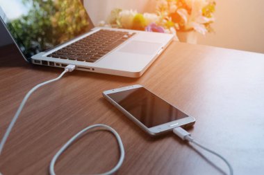Tapa içinde Usb kablosu şarj ahşap zemin üzerinde dizüstü bilgisayar ile hareket eden telefon