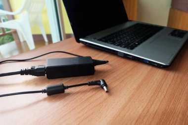 Ahşap bir masa üzerinde dizüstü bilgisayarın adaptör güç kablosu şarj
