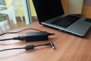 Ahşap bir masa üzerinde dizüstü bilgisayarın adaptör güç kablosu şarj