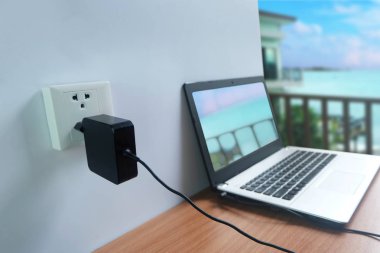 Güç kablosu şarj dizüstü bilgisayar ahşap zemin üzerinde beyaz bir duvar üzerinde takın