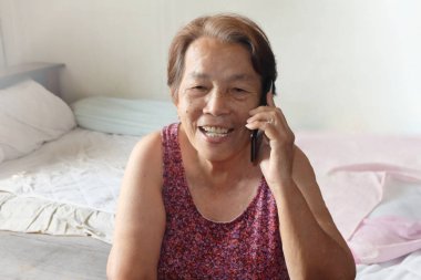 Yaşlı Asyalı kadın cep telefonu gülümseyen çağırıyor