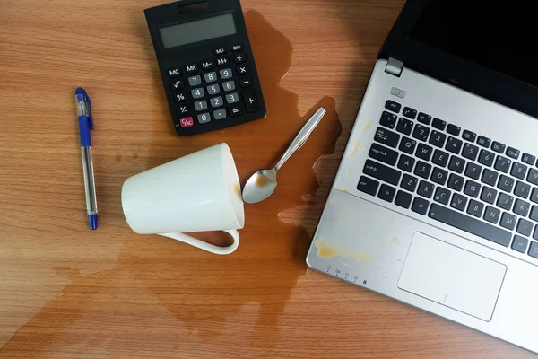 Coffee Cup spill out on Keyboard Laptop computer and smartphone on wooden floor,Cause damage Accident computer repair concept.