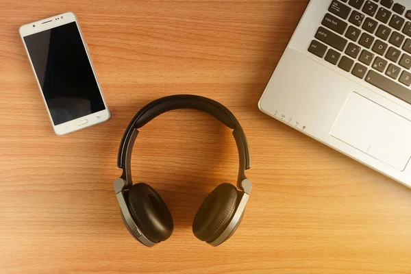 Aşırı kulak kulaklık ve ahşap zemin, kullanılan elektronik becerikli, üstten görünüm üzerinde dizüstü bilgisayar ile akıllı telefon