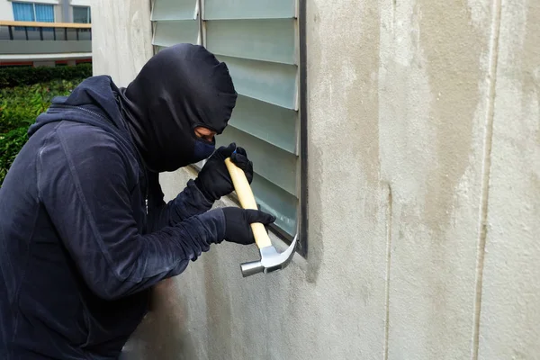 窓を破るしようとすると ハンマーを使用してマスクの泥棒 — ストック写真