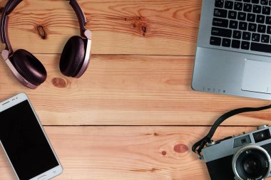 Aşırı kulak kulaklık ve akıllı telefon ve ahşap zemin, kullanılan elektronik becerikli, kopya alanı ile üstten görünüm üzerinde dizüstü bilgisayar ile film kamera