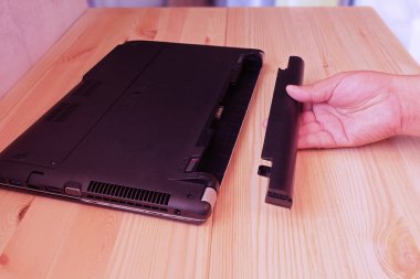 Pil dizüstü bilgisayarın kaldır ahşap zemin üzerinde tutan el yükseltme ve onarım bilgisayar kavramı.