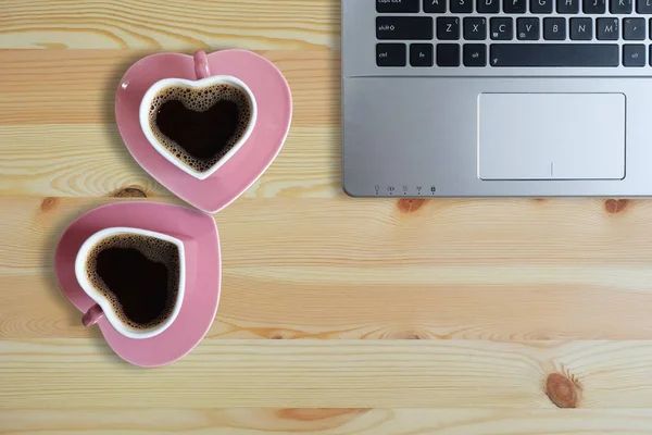 Black coffee in two pink cups heart shape and laptop computer on wooden floor, Copy space or empty space for text, Valentine day The lovers are together concept