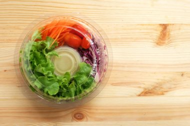 Taze salata ile yeşil meşe sebzeler, kiraz domates, rendelenmiş havuç ve mayonez salata sos krem ahşap zemin üzerinde net bir plastik kutu, Yemeye hazır