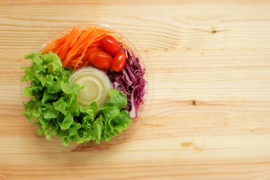 Taze salata ile yeşil meşe sebzeler, kiraz domates, rendelenmiş havuç ve mayonez salata sos krem ahşap zemin üzerinde net bir plastik kutu, Yemeye hazır