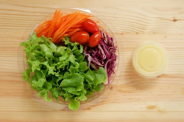 Taze salata ile yeşil meşe sebzeler, kiraz domates, rendelenmiş havuç ve mayonez salata sos krem ahşap zemin üzerinde net bir plastik kutu, Yemeye hazır
