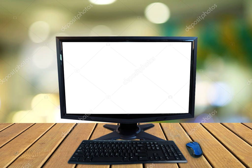 Computer desktop pc with blank screen and keyboard and wireless mouse on wooden floors with blurred colorful bokeh background