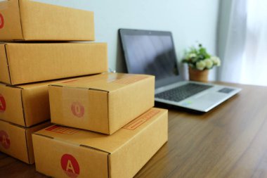 Laptop bilgisayar ve ürün kutusu ya da kargo paketi ahşap masa, online alışveriş, evde çalışmak, ticaret