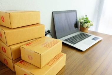 Laptop bilgisayar ve ürün kutusu ya da kargo paketi ahşap masa, online alışveriş, evde çalışmak, ticaret