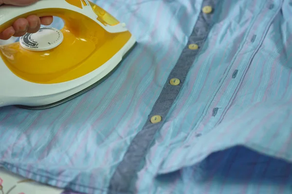 Hands Holding Orange Iron Ironing Wrinkled Shirt Selective Focus — Stock Photo, Image