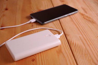 Akıllı telefon yedek batarya ya da masa tahtasındaki beyaz güç bankasıyla şarj oluyor.