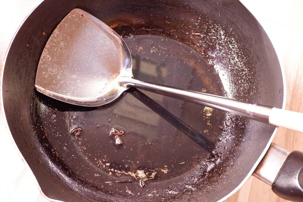The pan is dirty, burnt and black, and has oil stains.