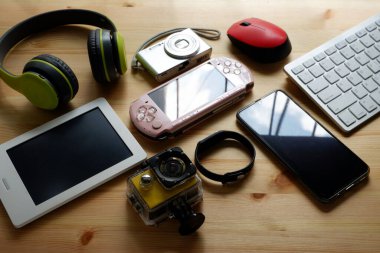 Akıllı telefon, portatif oyun konsolları, kitap okuyucu ve diğer elektronik aletlerle ahşap zeminde..
