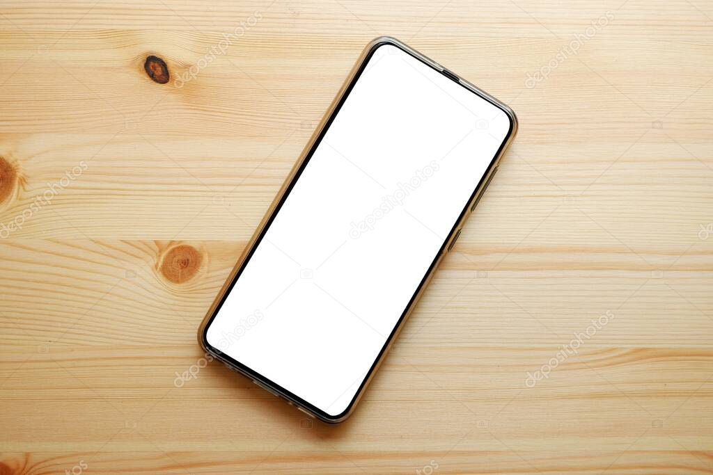 Smartphone with blank white screen on wooden background.Top view.