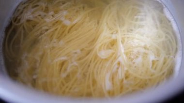Tavada spagetti kaynayan suda pişiyor.