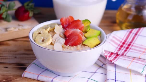 Havregrynsgröt med banan, jordgubbar och avokado. Friska veganska frukost — Stockvideo