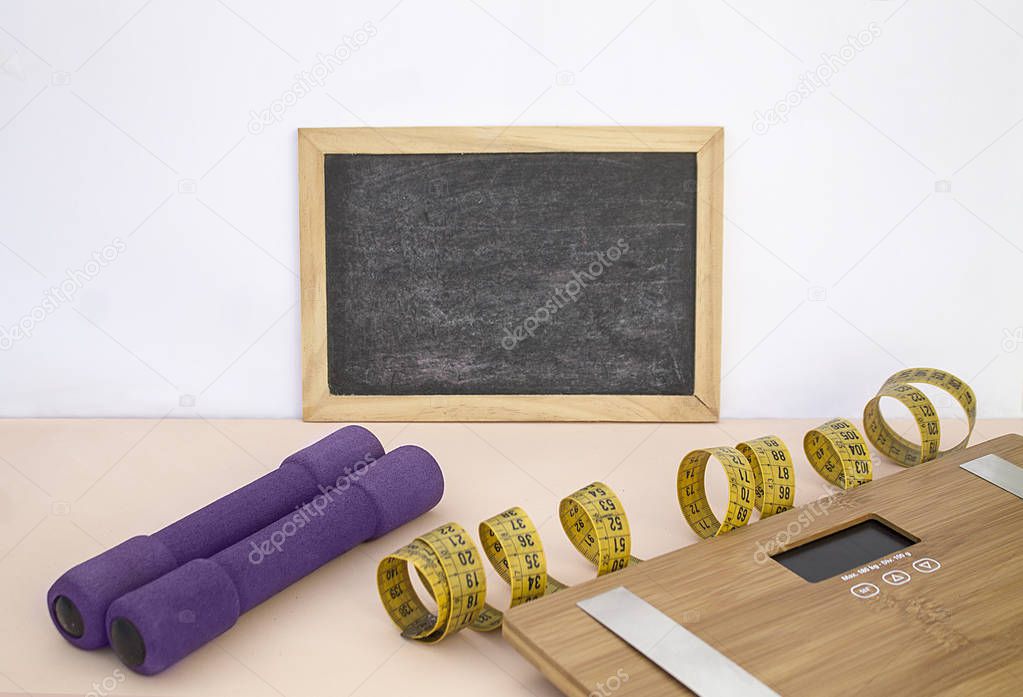 Pizarra en blanco, pesas, cinta metrica y bascula. Blank blackboard, dumbbells, tape measure and scale.