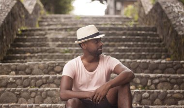 Siyah bir adam portresi / Hint adam uzakta kameradan arayan turist olarak eski bir köy sokaklarında bir merdiven üzerinde oturan