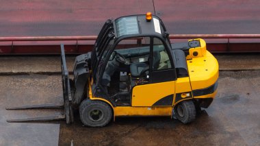 Sarı forklift ıslak beton yüzeye park edilmiş. Sanayi bölgesi.