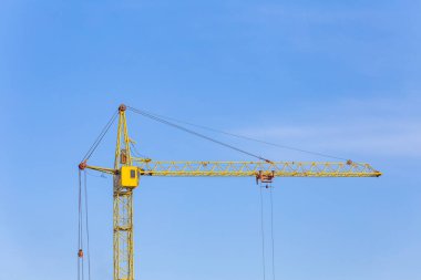 Sarı bir vinç görüntüsü. Mavi gökyüzü arka planı. Uzun flok yelkeni. İnşaat alanı.