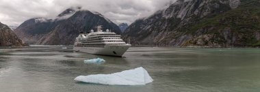 Tracy Arm Fjord, Alaska, ABD - 23 Ağustos 2018: Seabourn Sojourn yolcu gemisi Panorama önplanda yüzen dev bir buzdağıyla sürükleniyor