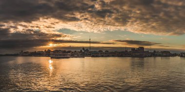 Günbatımında Belize şehrinin güzel panoramik manzarası. İnanılmaz turuncu gökyüzü bulutlar ve güneş suya yansıyor.