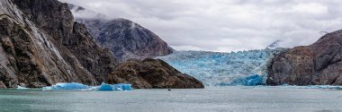 Sawyer Buzulu 'nun muhteşem panoramik manzarası üzerinde küçük bir tekne yüzüyor ve buzdağları Alaska' nın Tracy Arm Fjords Terör Vahşeti 'nde yüzüyor.