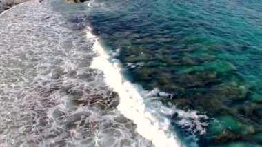 Karayipler 'deki Aruba sahillerine düşen dalgaların, Kaliforniya deniz fenerinin yanındaki Hollanda Antilleri' nin insansız hava aracı görüntüsü. Turkuaz su ve kayalık plaj. Suyun üzerinde yükselen açılı kamera görüntüsü.