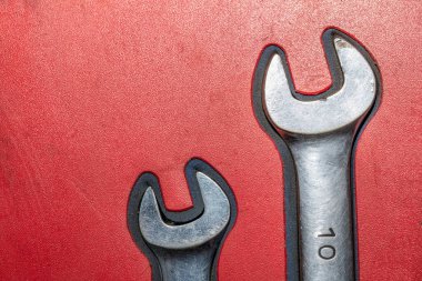 Kırmızı arkaplanda iki eski krom anahtarın yakın çekimi.