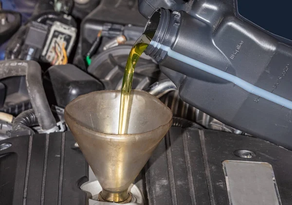 エンジンへの漏斗を介して油のパイントを注ぐ車の中で油をトッピング機械 油や漏斗の閉じる — ストック写真