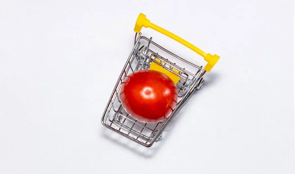 白い背景に隔離されたショッピングカートで1つのトマトのショット 最上階だ ショッピングカートでおいしい赤いトマトを熟す トマト取引の概念 オンラインショッピングのコンセプト スペースのコピー — ストック写真
