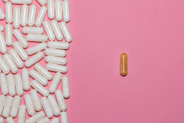 一边是白色药丸的顶部视图 另一边是粉色背景的单个棕色药丸 具有复制空间 医疗和制药概念 — 图库照片
